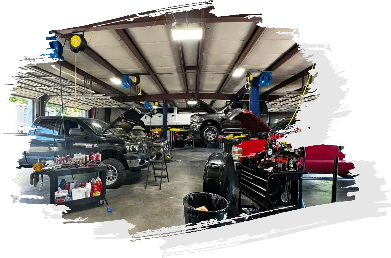 Auto repair shop with vehicles on lifts, tools, and equipment around. Open hoods and organized workstations are visible. Performance upgrade in Oak Ridge, TN, with Bootlegger Industries