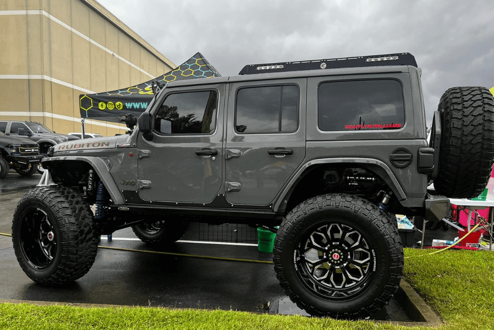 overlanding, Performance Upgrades and Customization Experts in Oak Ridge, TN at Bootlegger Industries. Lifted Jeep Wrangler Rubicon with oversized off-road tires and custom suspension parked at an outdoor automotive event under cloudy skies.